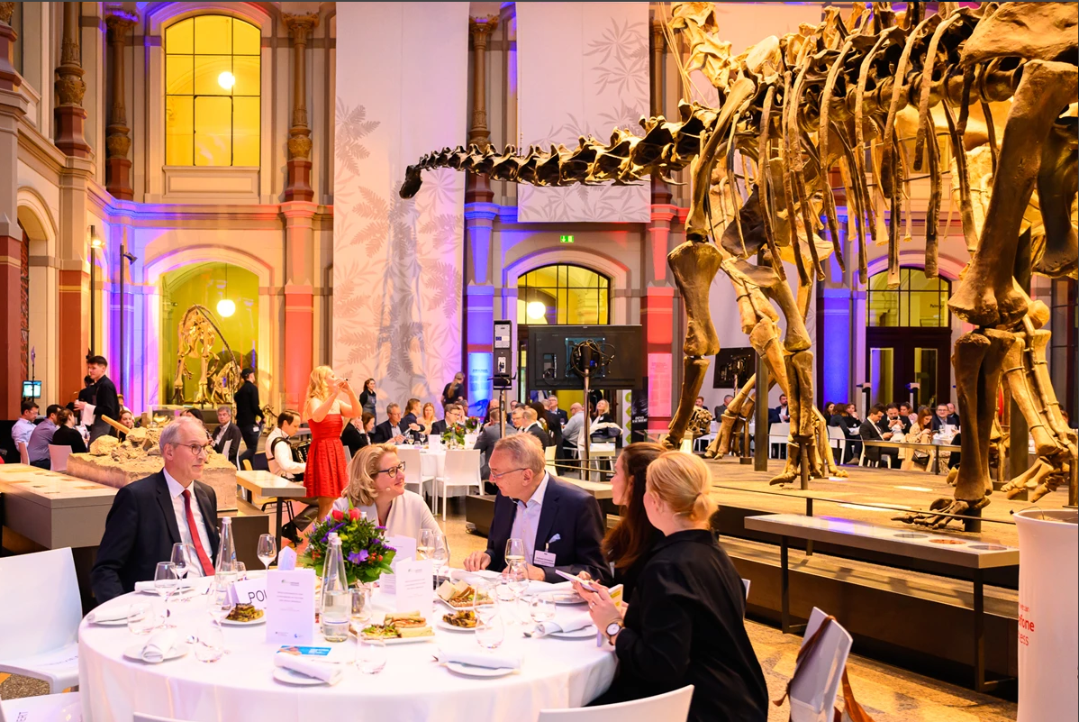 Teilnehmende der Veranstaltung am Tisch im Dinosauriersaal.