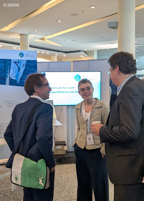 Caroline Werner ist in einem Gespräch mit zwei Interessierten am Stand der IEEKN.