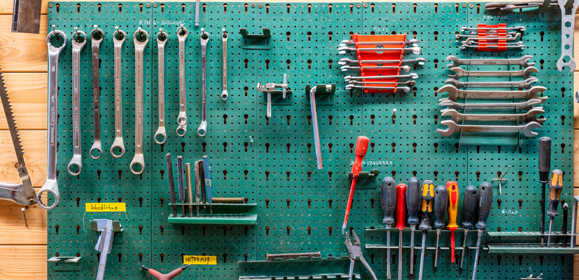 Werkzeugkasten: Werkzeug hängt an einer grünen Wand.