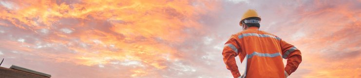 Bauarbeiter arbeiten im Sonnenuntergang an einem Dachstuhl.