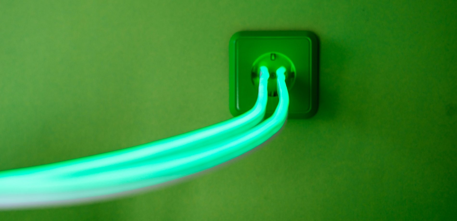 Eine grüne Steckdose wird angezeigt. Aus ihr fließt grüner Strom in grellen Farben.