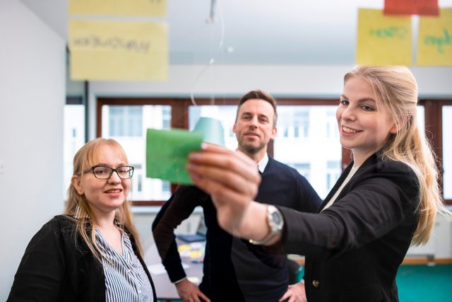 Ein Workshop dreier Personen, die Notizzettel auf eine Glasscheibe kleben.
