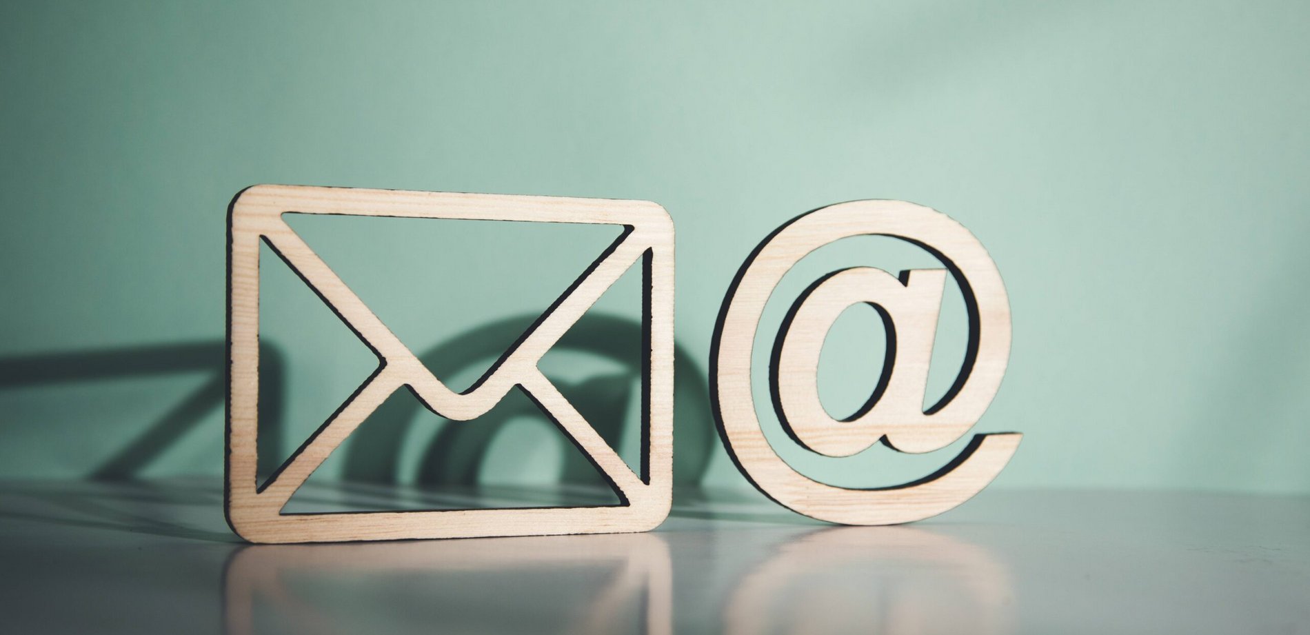 Hölzerner Briefumschlag und E-Mail-Symbol @ auf Tisch.