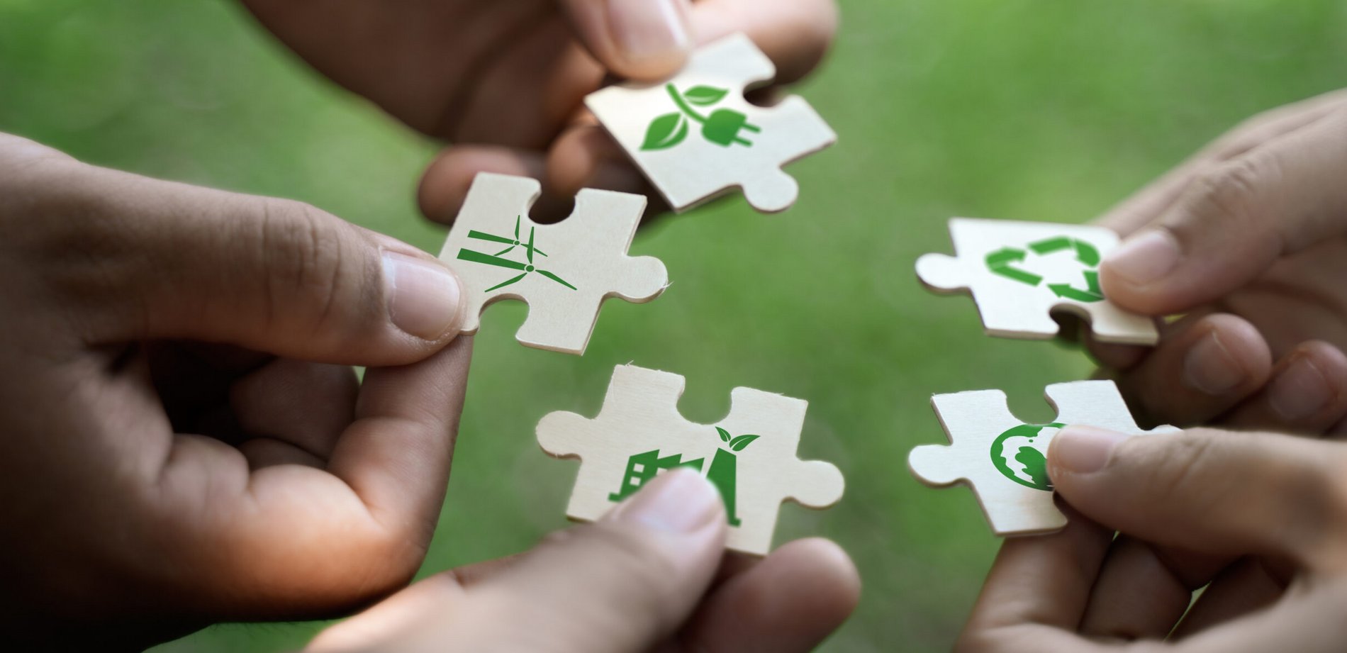 Hände halten Puzzleteile mit Nachhaltigkeitssymbolen