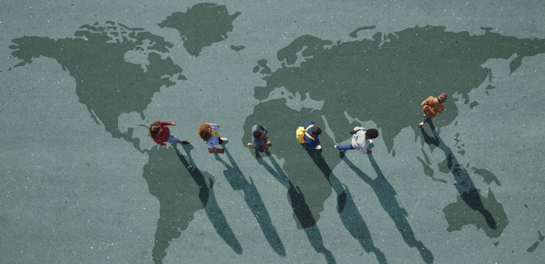 People walking in a line on the ground that depicts the outlines of the Earth.