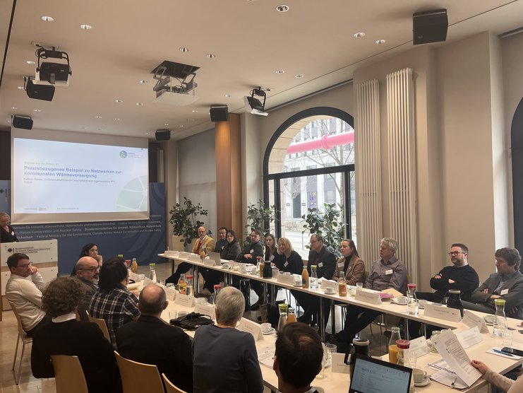 Das Bild zeigt die Teilnehmenden des Workshops "Intensivierung der Zusammenarbeit zwischen kommunalen Akteuren", die an einem U-förmigen Tisch sitzen. .