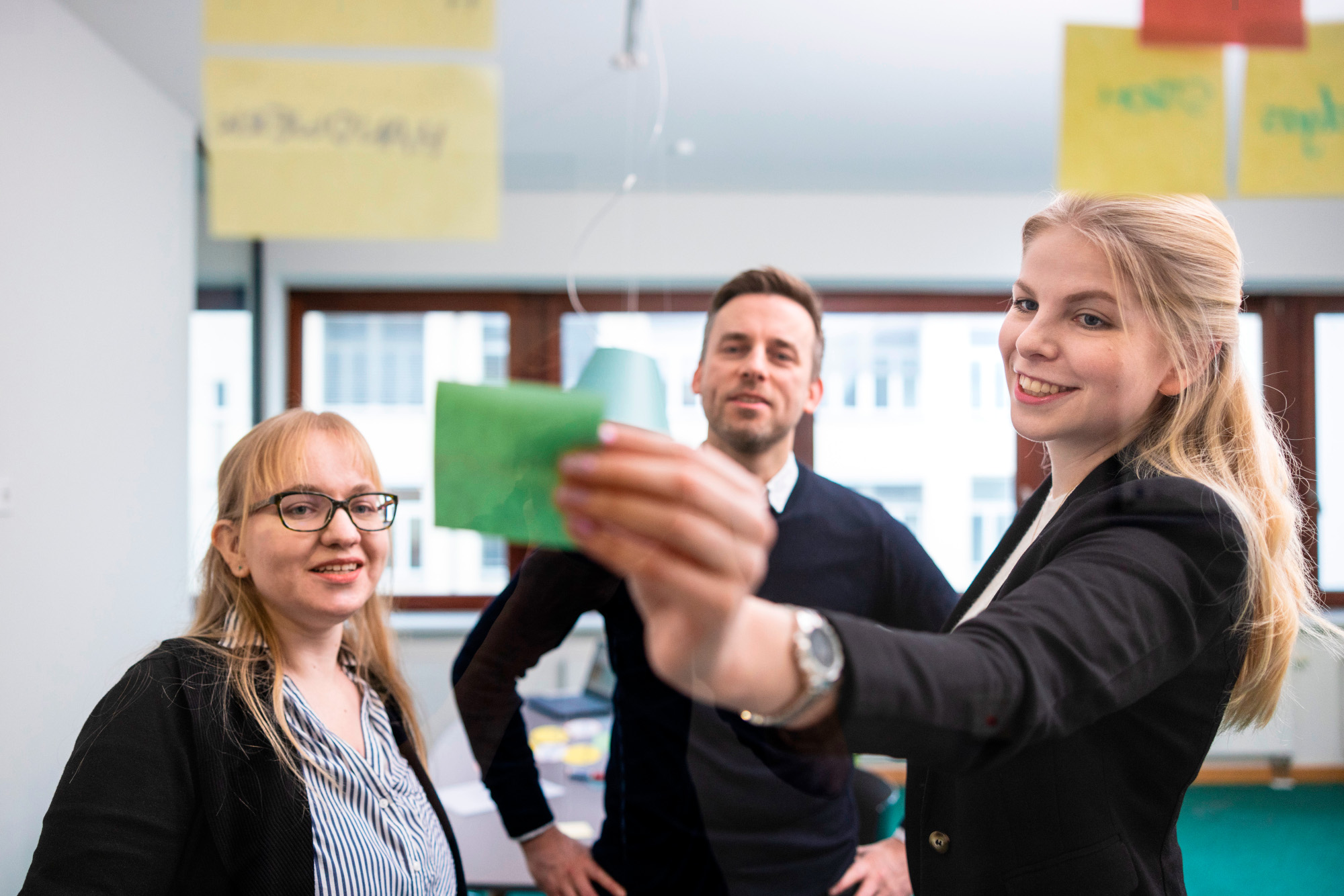 Ein Workshop dreier Personen, die Notizzettel auf eine Glasscheibe kleben.